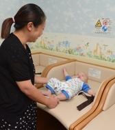 お母さんがおむつ交換台で赤ちゃんのおむつを替えようとしている写真