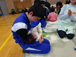 男子中学生が赤ちゃんを抱っこしてあかちゃんの顔をじっと見ている写真