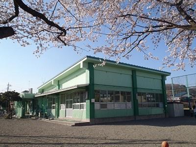 桜が咲く季節に撮影された緑色の外壁の川口児童館の外観写真