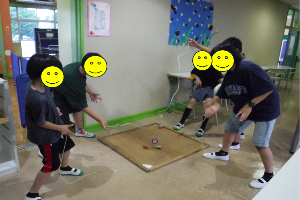 小学生がロビーでコマを回す様子