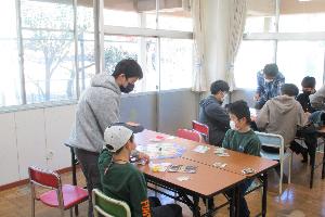 児童館で中学生が小学生にボードゲームを教えている様子の写真