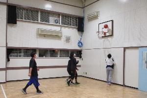 児童館の遊戯室でバスケットボールを楽しむ男子中学生と高校生の写真