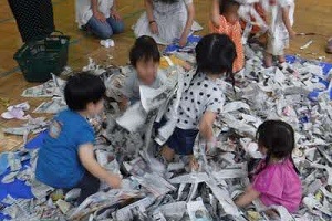 児童館内での乳幼児活動で新聞紙あそびをしている子どもたちの写真