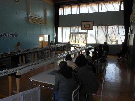 たくさんの家族が部屋いっぱいのプラレールで遊んでいる様子